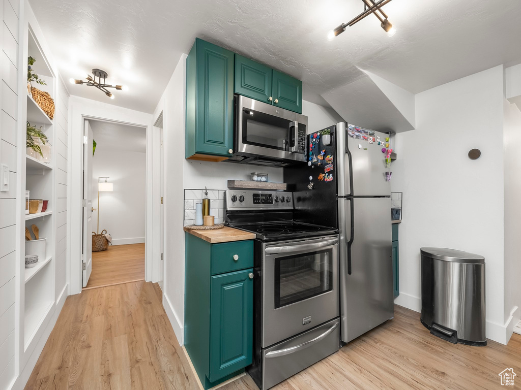 Kitchen with stainless steel appliances, butcher block counters, light wood-style floors, and baseboards