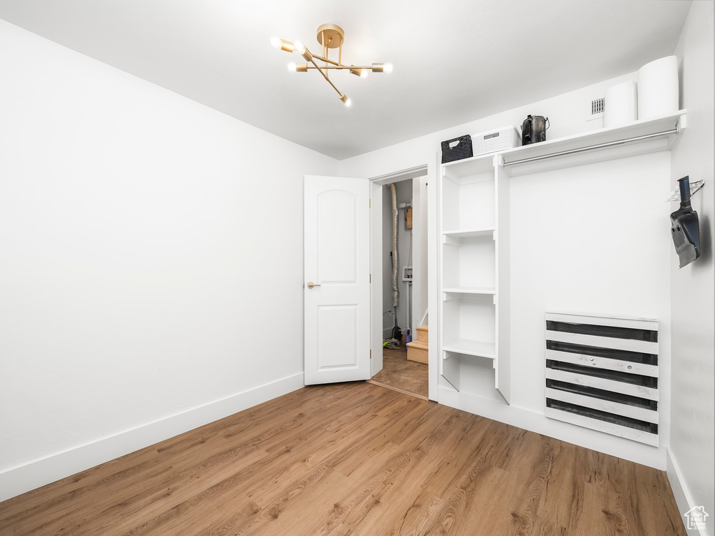 Unfurnished bedroom with a closet, a notable chandelier, baseboards, and wood finished floors