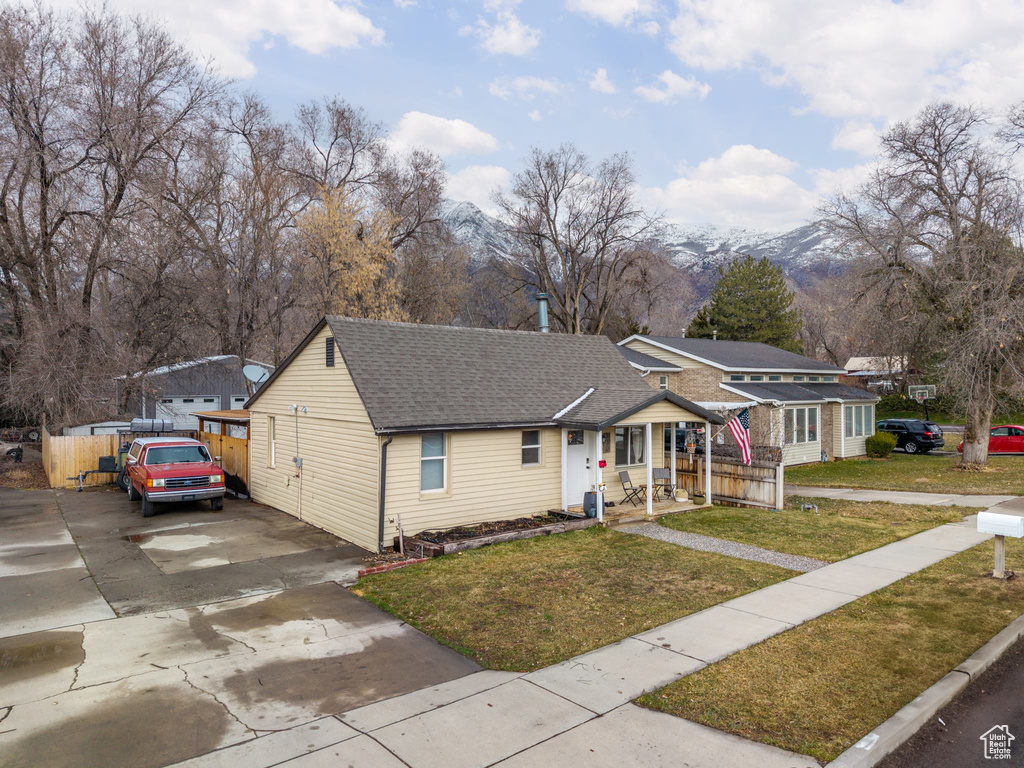 Bungalow featuring driveway, a front lawn, a shingled roof, and fence