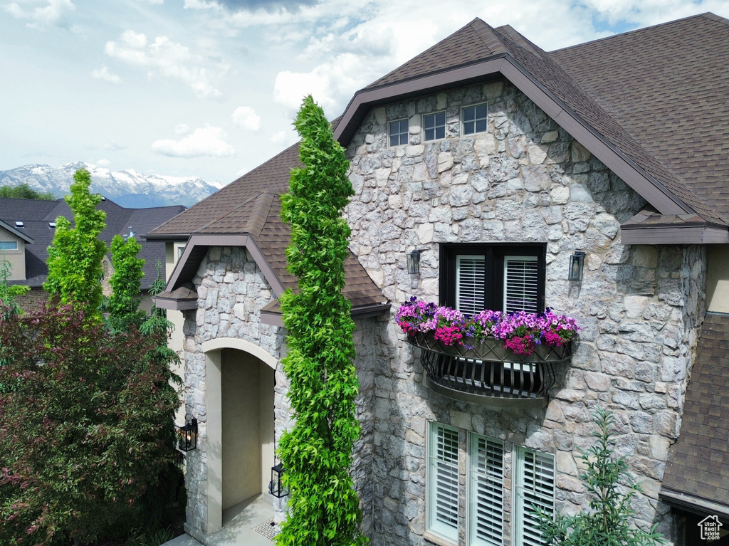 View of front of home featuring stone siding and roof with shingles