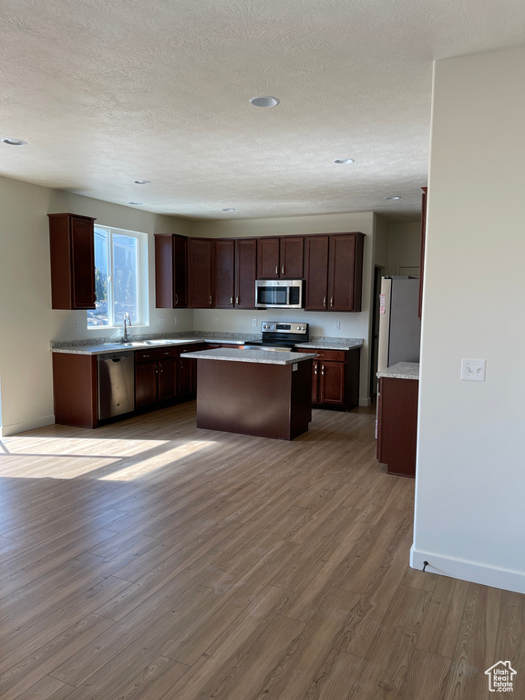 Kitchen featuring light countertops, light wood finished floors, appliances with stainless steel finishes, and a kitchen island
