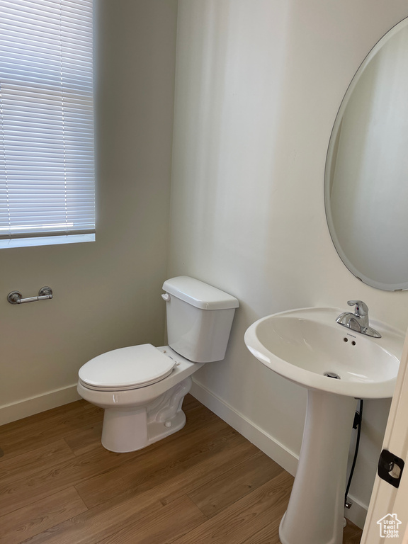 Half bath featuring baseboards, toilet, and wood finished floors