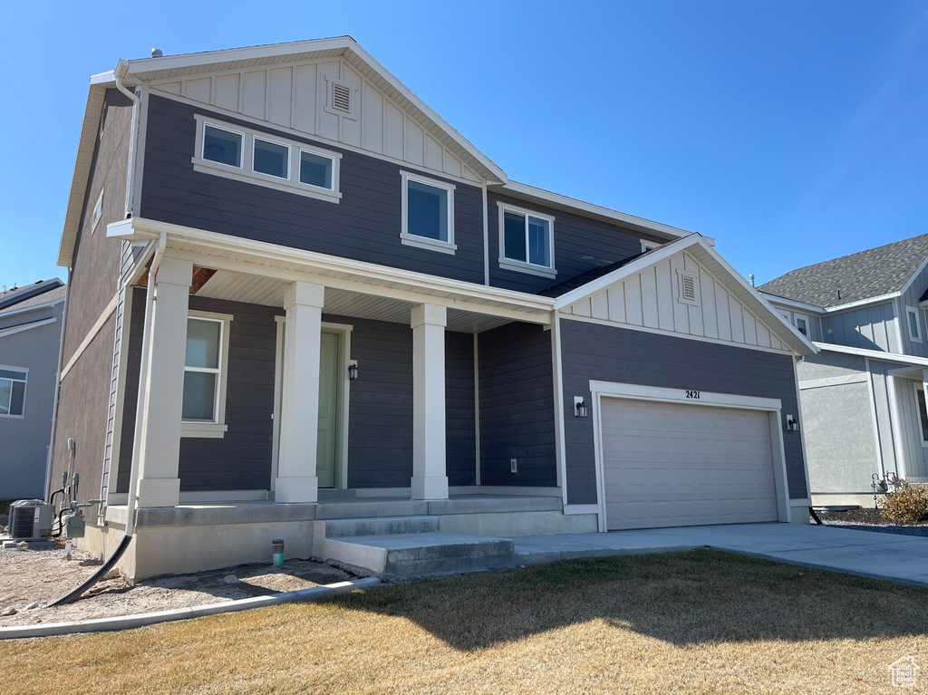 View of front of home with cooling unit, driveway, a porch, a garage, and board and batten siding