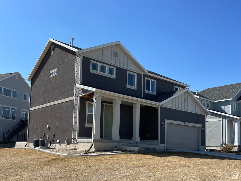 View of front of home featuring covered porch, an attached garage, central AC unit, and board and batten siding