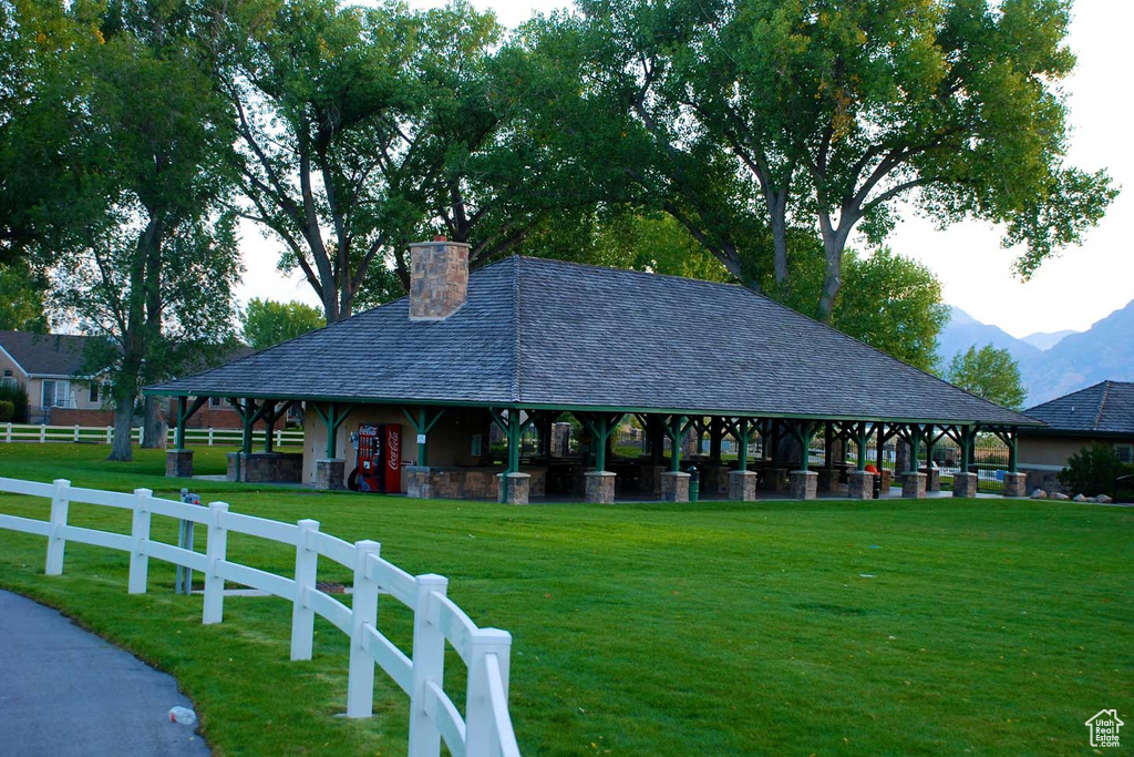 View of community featuring a mountain view, a lawn, and fence