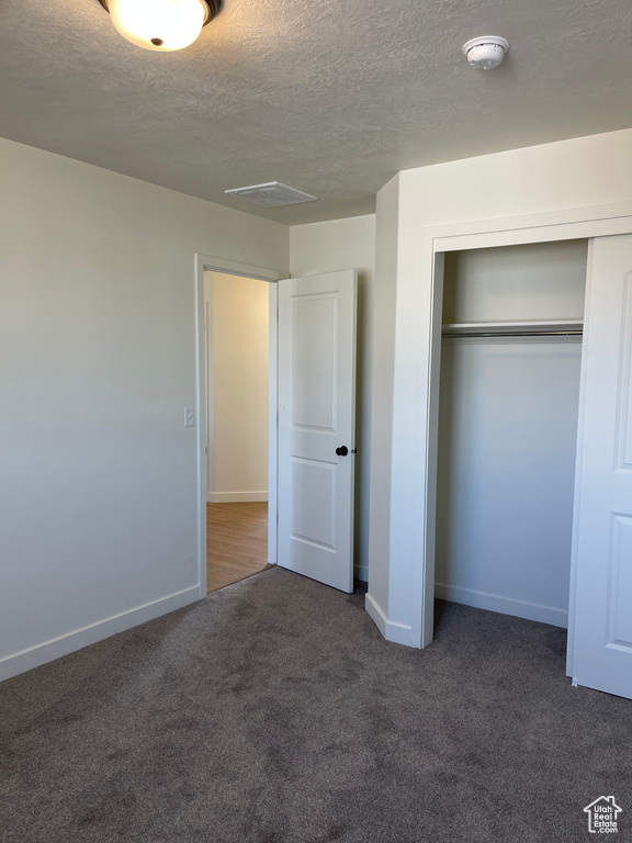 Unfurnished bedroom featuring a closet, baseboards, carpet, and a textured ceiling