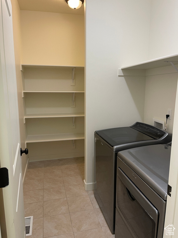 Laundry area featuring light tile patterned floors, separate washer and dryer, baseboards, and visible vents