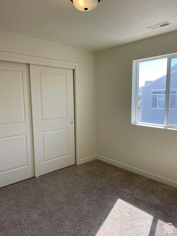 Unfurnished bedroom with a closet, visible vents, baseboards, and carpet