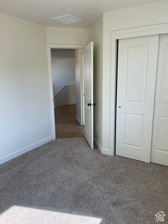 Unfurnished bedroom with a closet, visible vents, baseboards, and carpet floors