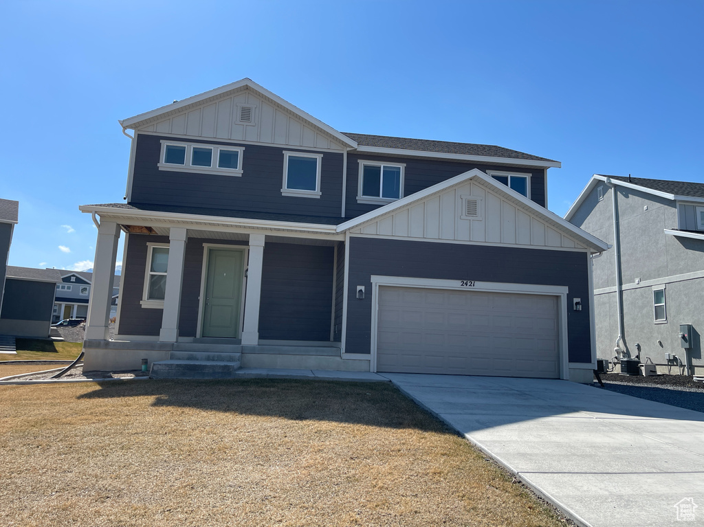 View of front facade featuring covered porch, board and batten siding, concrete driveway, and a garage