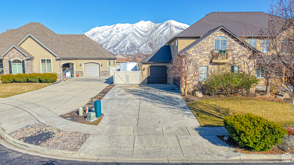 French country inspired facade with concrete driveway, stucco siding, stone siding, an attached garage, and a gate