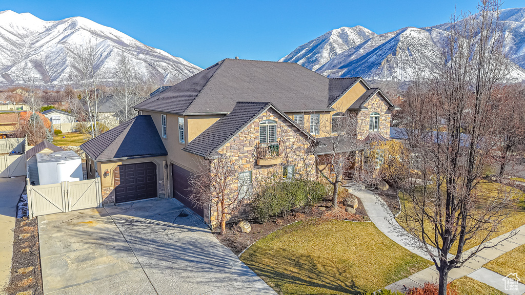 View of front of property featuring stucco siding, stone siding, driveway, and a gate