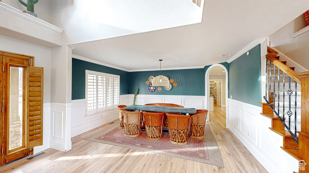 Dining space with stairs, a wainscoted wall, arched walkways, and visible vents