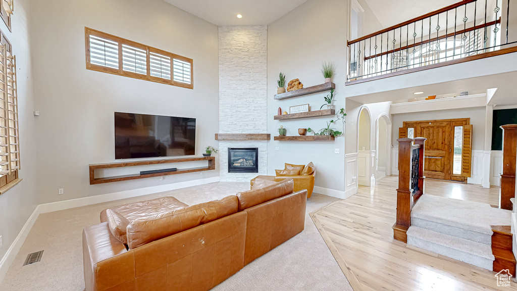 Living area featuring visible vents, a stone fireplace, a high ceiling, and baseboards