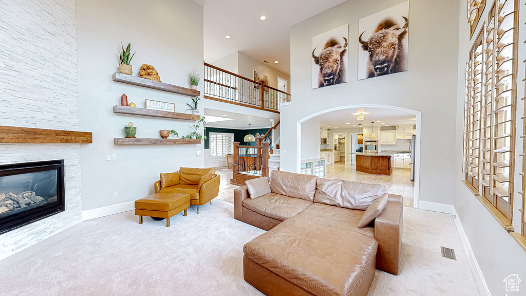 Living room with stairs, light colored carpet, visible vents, and a fireplace