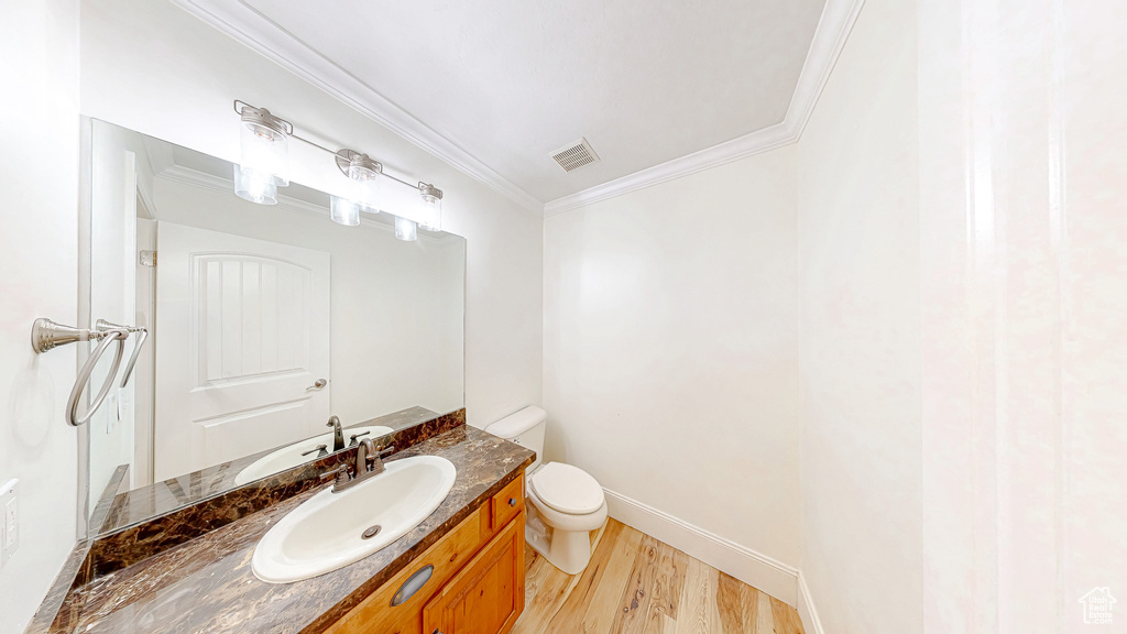 Bathroom featuring visible vents, toilet, wood finished floors, crown molding, and vanity