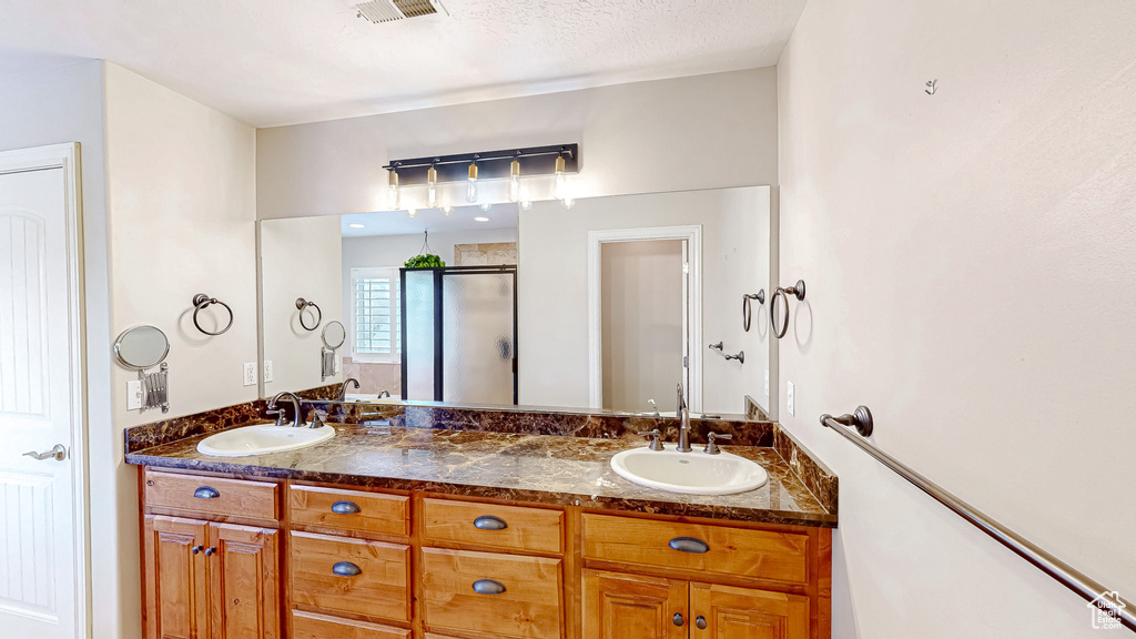 Bathroom with a sink, visible vents, double vanity, and a shower stall