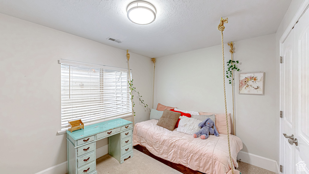 Bedroom featuring visible vents, light colored carpet, a textured ceiling, and baseboards