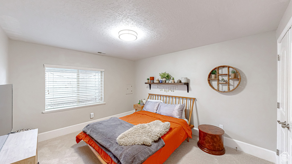 Carpeted bedroom with visible vents, a textured ceiling, and baseboards