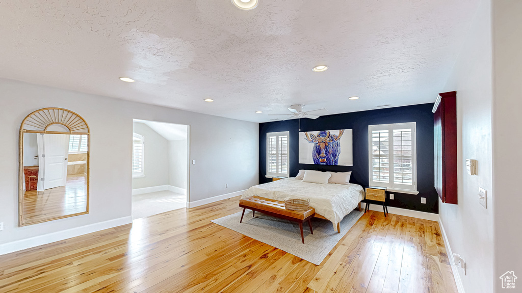 Bedroom with multiple windows, light wood-style floors, and a textured ceiling