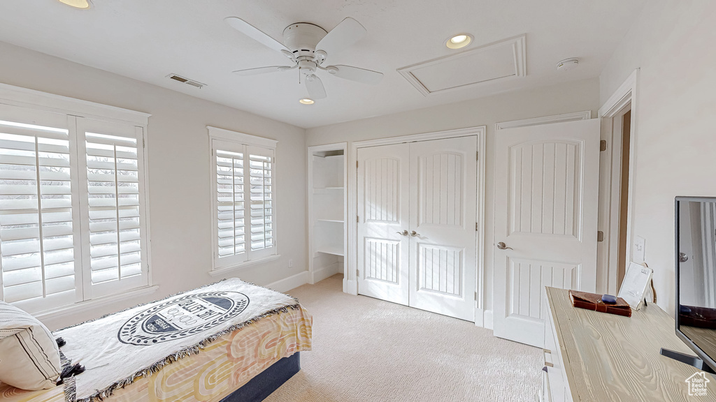 Bedroom with a ceiling fan, visible vents, attic access, a closet, and light carpet