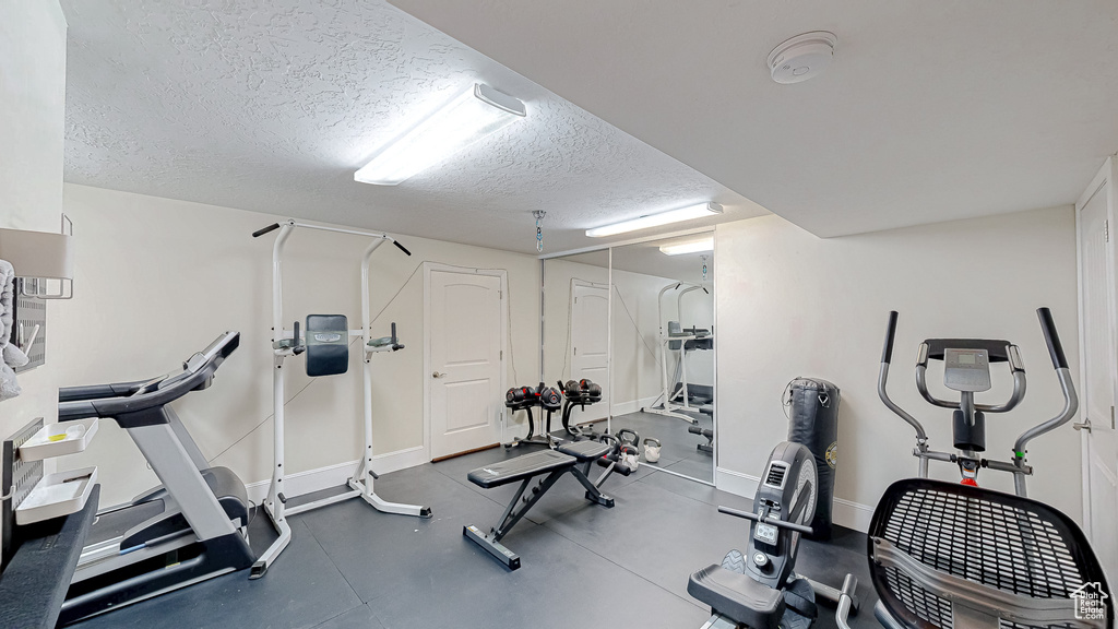 Exercise room with baseboards and a textured ceiling