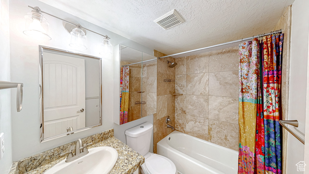 Full bathroom featuring visible vents, toilet, a textured ceiling, shower / bath combination with curtain, and vanity