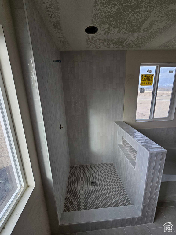 Full bathroom with tile patterned flooring, a tile shower, and a textured ceiling