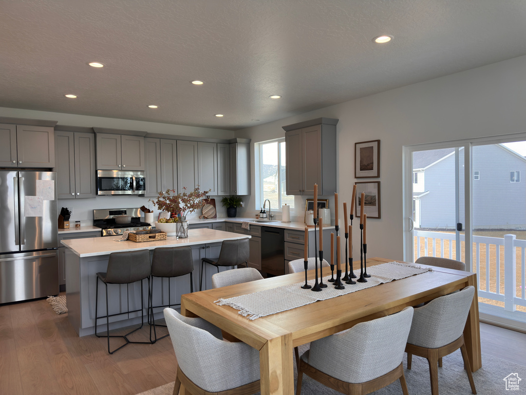 Kitchen featuring gray cabinetry, light wood-style flooring, a center island, appliances with stainless steel finishes, and light countertops