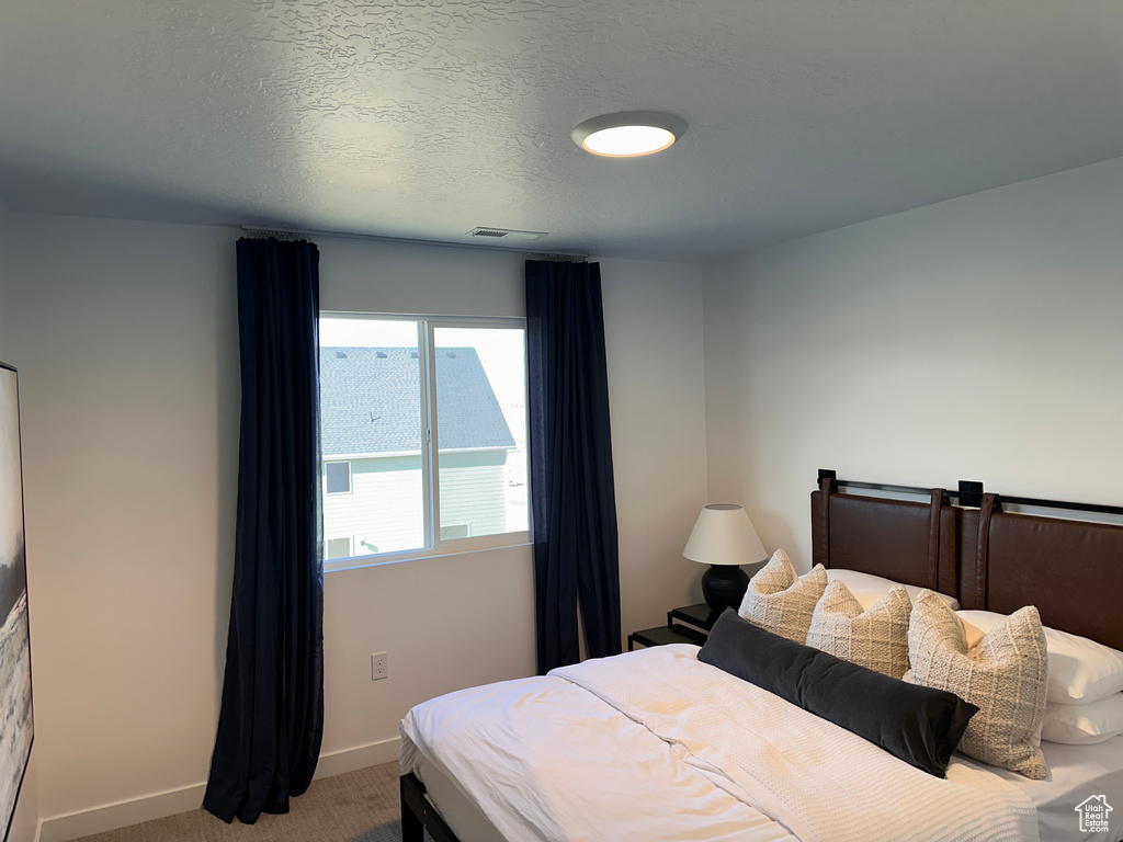 Bedroom with visible vents, baseboards, a textured ceiling, and carpet flooring