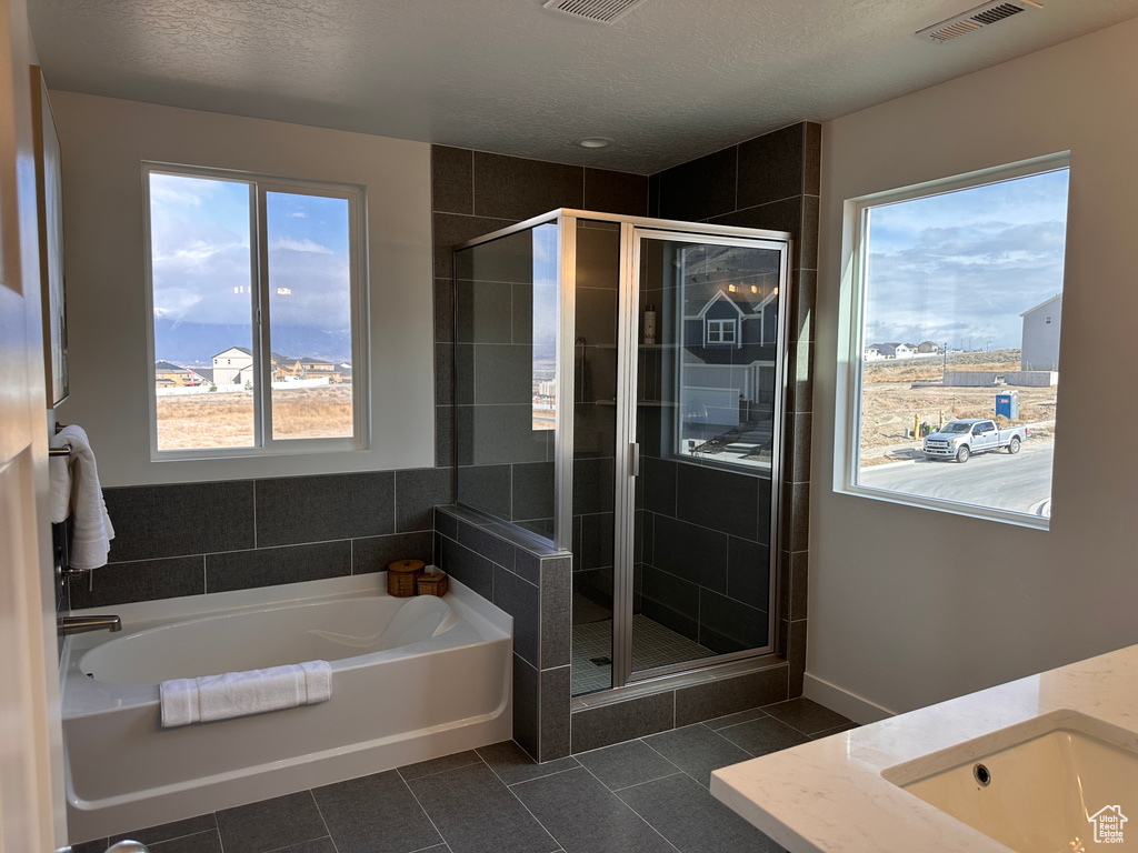 Full bathroom with tile patterned floors, visible vents, a stall shower, and a bath