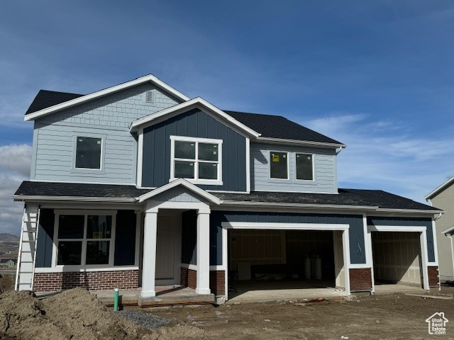 Craftsman inspired home with brick siding, board and batten siding, and a garage