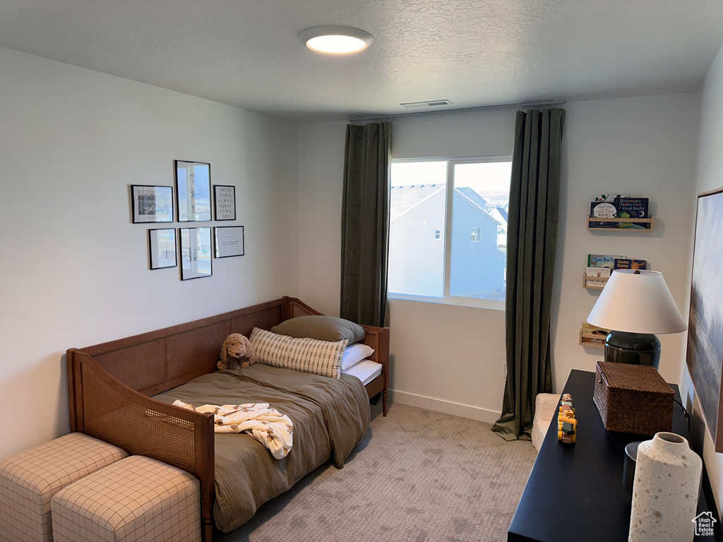 Bedroom featuring visible vents, light carpet, a textured ceiling, and baseboards