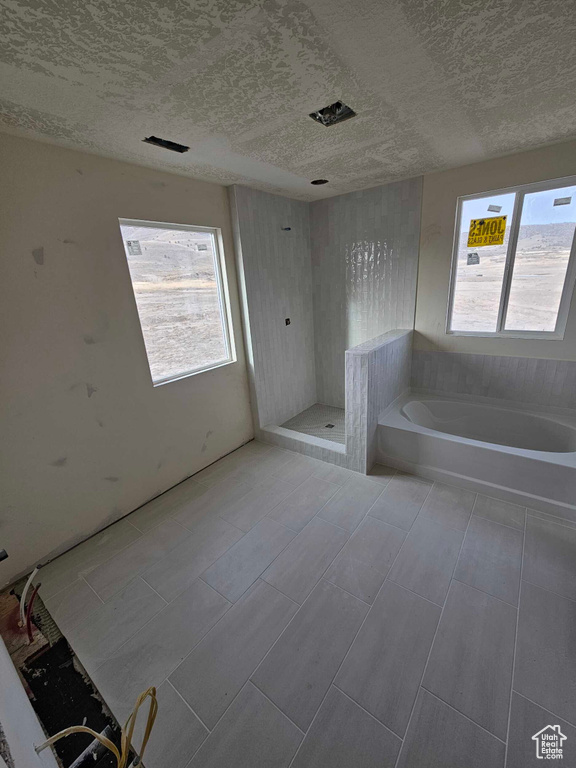 Full bath featuring a shower, a textured ceiling, and a bath