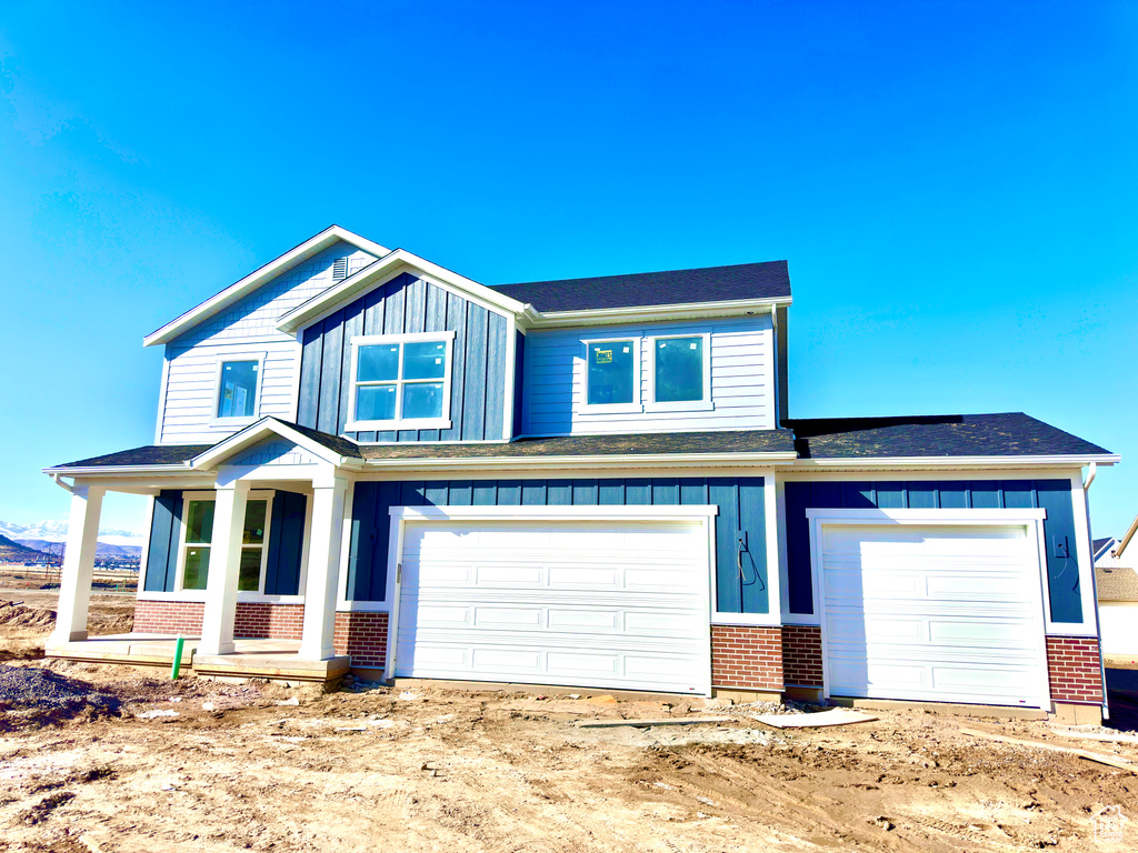 View of front of property with a garage, brick siding, and board and batten siding