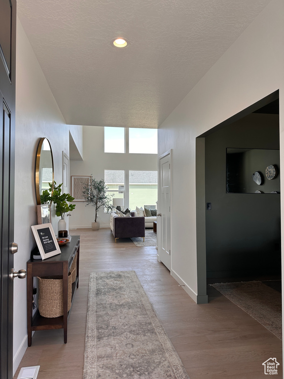 Hallway featuring wood finished floors, baseboards, and a textured ceiling