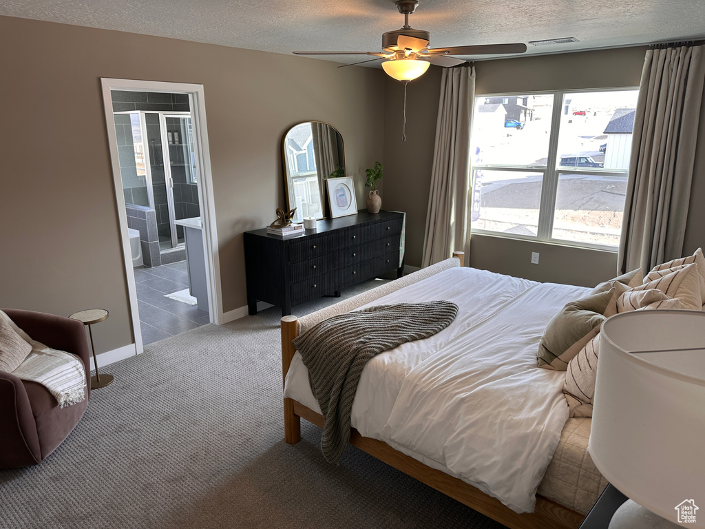 Bedroom featuring baseboards, carpet floors, ensuite bath, ceiling fan, and a textured ceiling