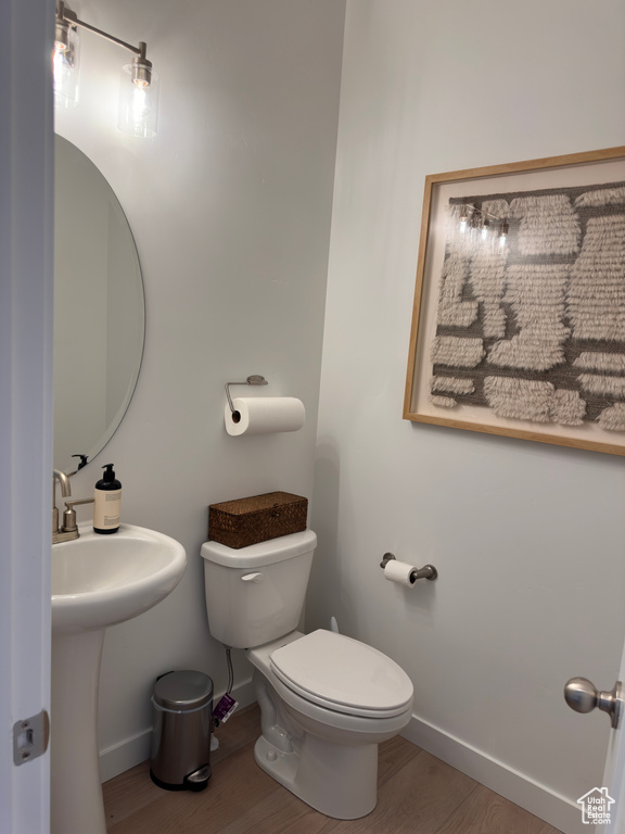 Bathroom with a sink, baseboards, toilet, and wood finished floors