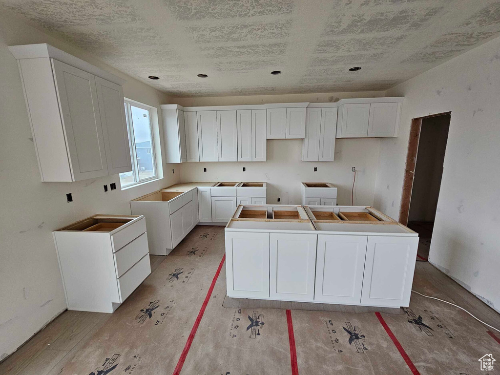 Kitchen featuring washer / clothes dryer, white cabinetry, and a center island