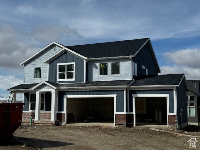 View of front facade with brick siding, board and batten siding, a garage, and dirt driveway