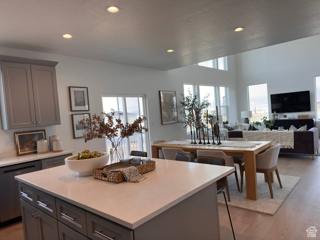 Kitchen featuring gray cabinetry, dishwasher, a kitchen breakfast bar, light wood-type flooring, and a center island