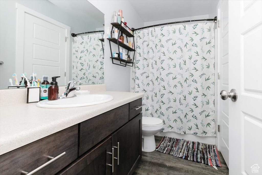 Bathroom featuring shower / tub combo with curtain, toilet, vanity, and wood finished floors