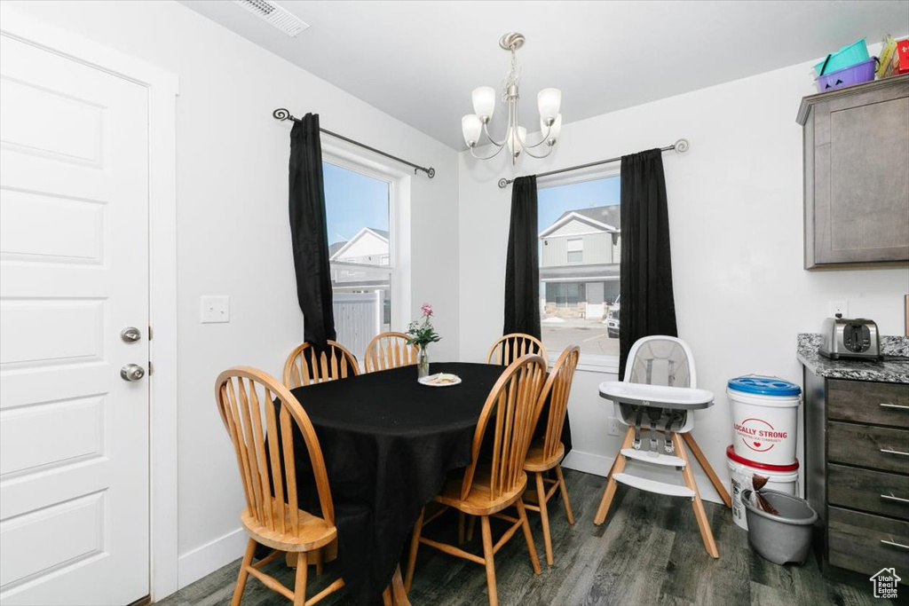 Dining space with a wealth of natural light, a chandelier, dark wood finished floors, and visible vents