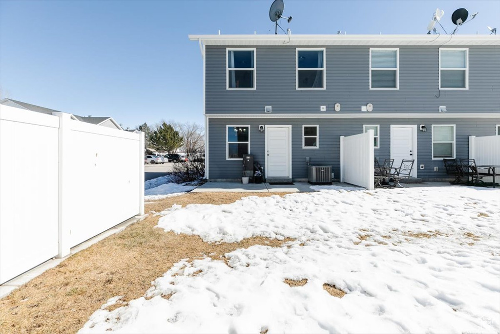Snow covered back of property with central AC