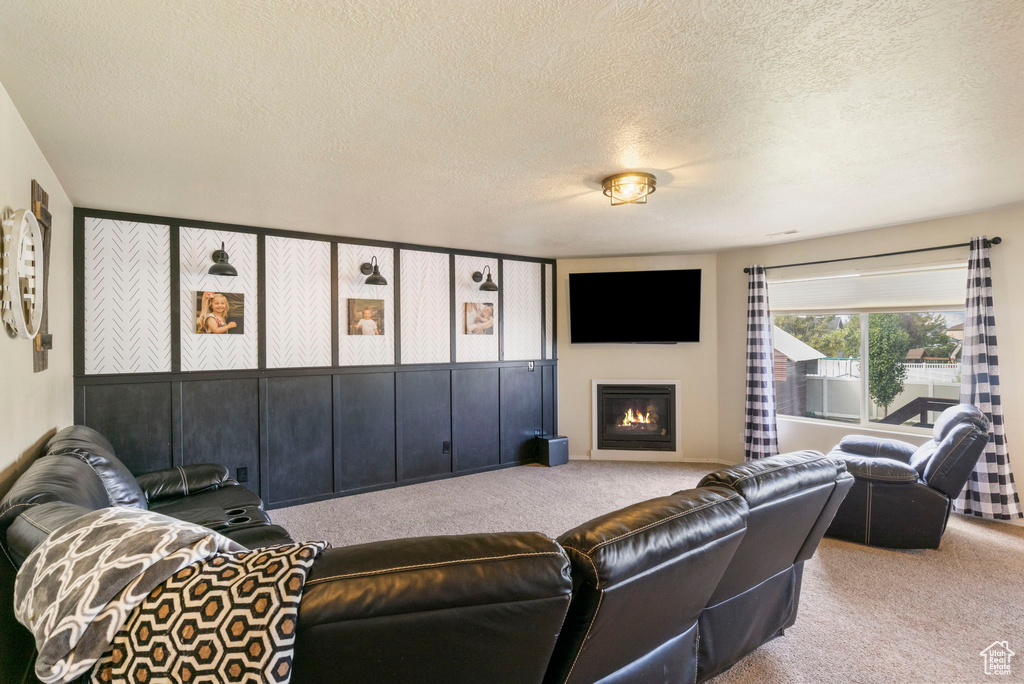 Living area featuring carpet, a warm lit fireplace, and a textured ceiling