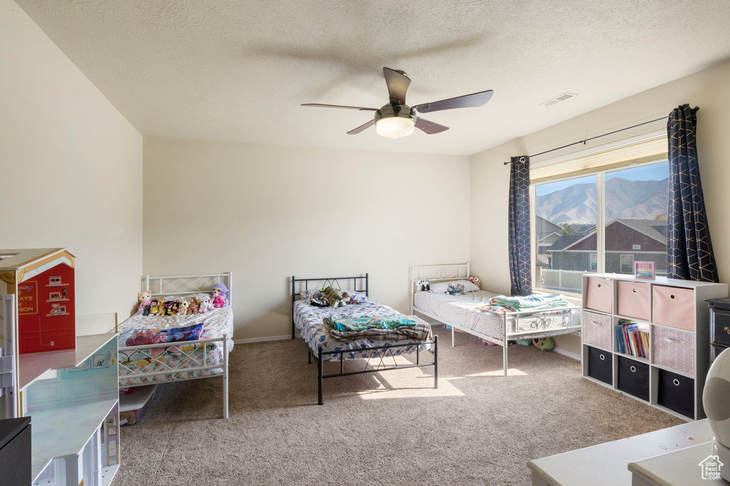 Bedroom with visible vents, a textured ceiling, a mountain view, carpet, and ceiling fan