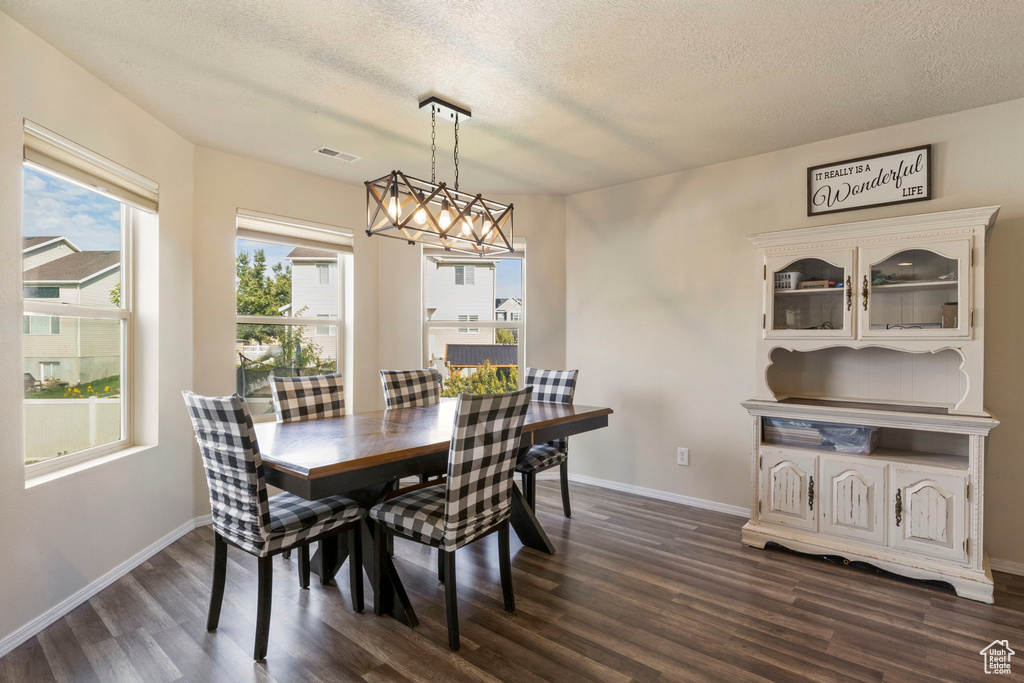 Dining area featuring baseboards, visible vents, an inviting chandelier, dark wood-type flooring, and a textured ceiling