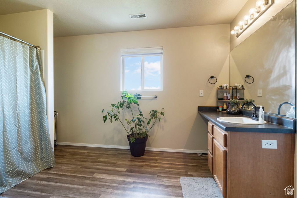 Bathroom with vanity, wood finished floors, visible vents, and baseboards