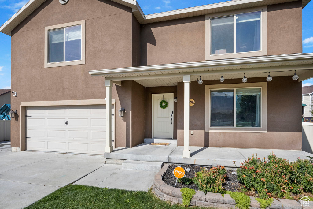 View of front facade with stucco siding, a garage, a porch, and concrete driveway