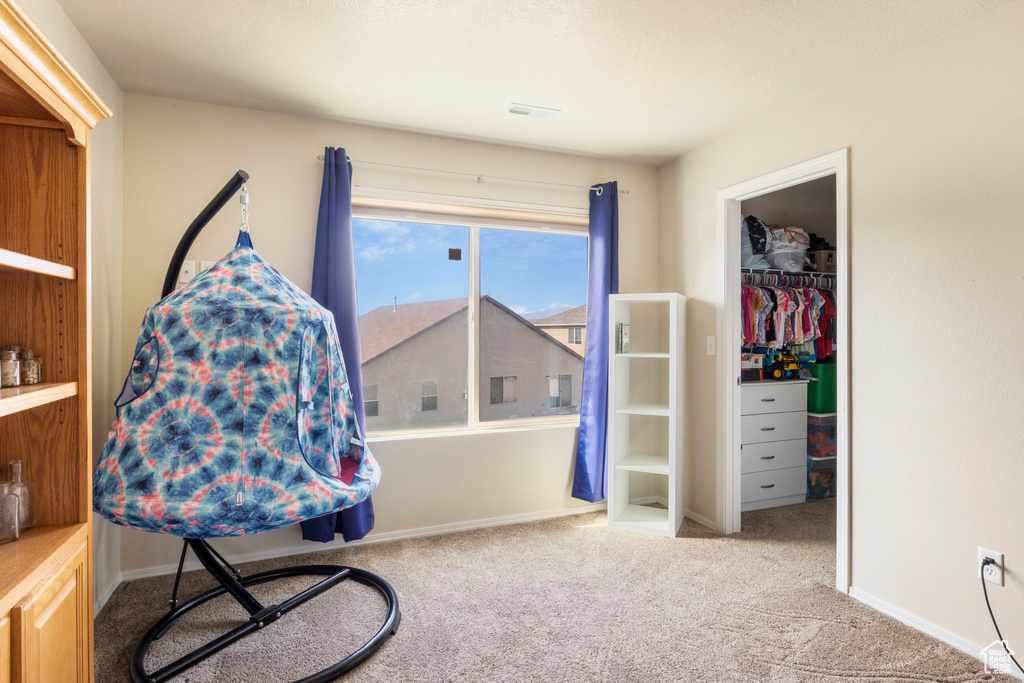 Bedroom featuring a closet, a walk in closet, baseboards, and carpet floors